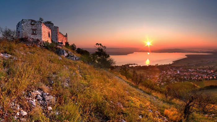 Romantická krajina, západ slunce a hrad na kopci