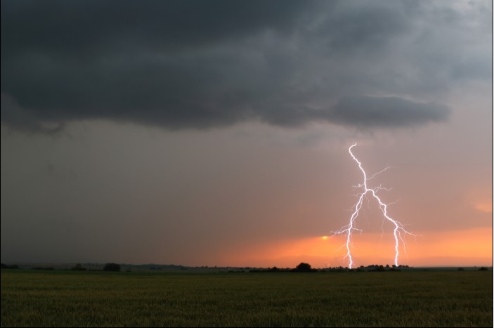 Bouřka při západu slunce, krásný bleskový výboj nad loukou